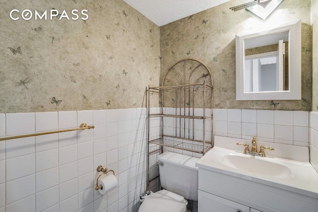 bathroom featuring vanity, a textured ceiling, tile walls, and toilet