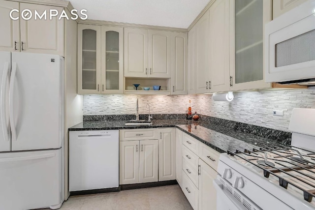 kitchen with white appliances, sink, decorative backsplash, and dark stone countertops