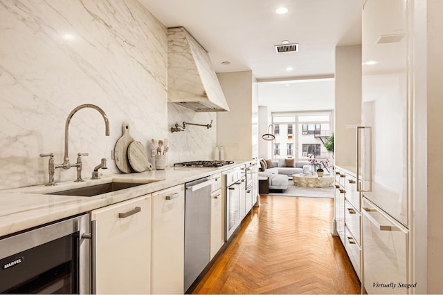 kitchen featuring beverage cooler, visible vents, a sink, premium range hood, and backsplash