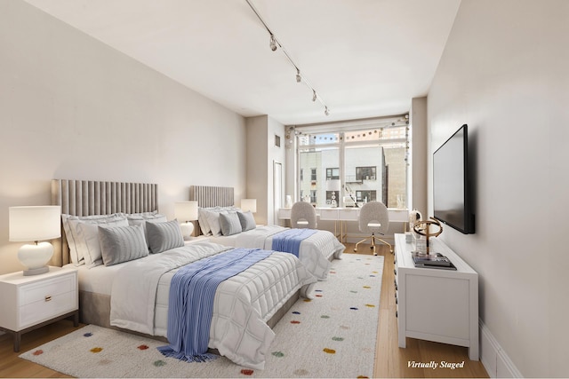 bedroom featuring rail lighting and wood finished floors