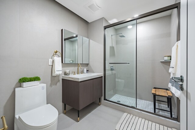 bathroom featuring vanity, a shower with shower door, and toilet