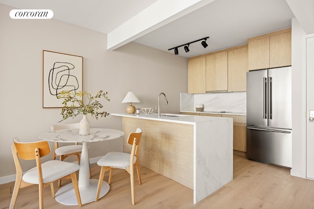 kitchen with sink, tasteful backsplash, light hardwood / wood-style flooring, light brown cabinets, and high quality fridge