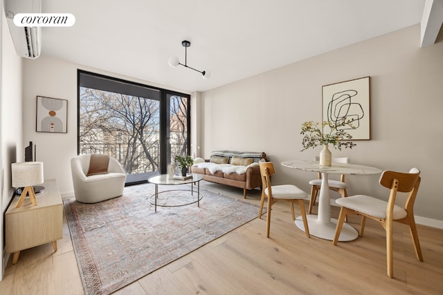 sitting room with wood-type flooring, a wall mounted AC, and a wall of windows