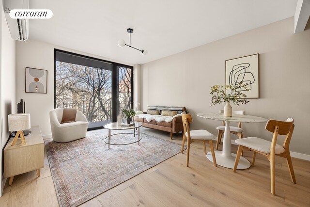 living area featuring a wall of windows, wood-type flooring, and a wall mounted air conditioner