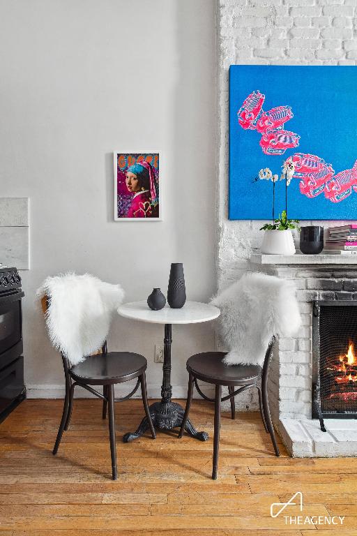 dining space with wood-type flooring and a brick fireplace