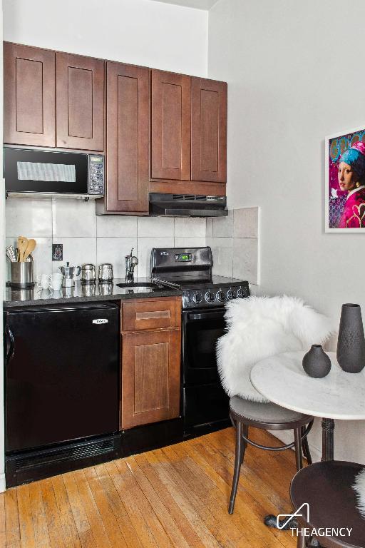 kitchen with backsplash, wood-type flooring, and black appliances