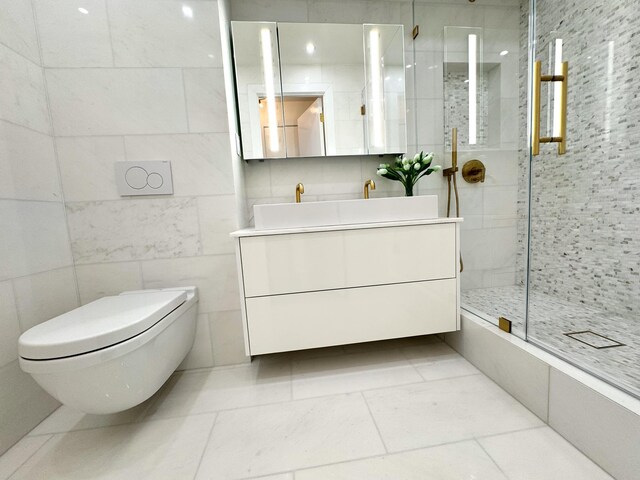 bathroom featuring a shower with door, vanity, tile walls, and toilet