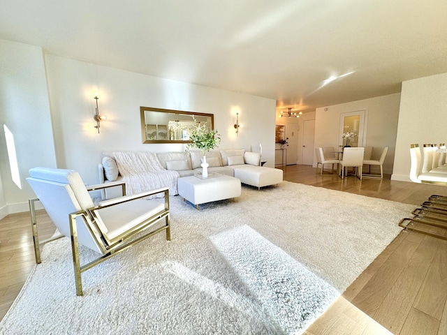 living area with baseboards, a chandelier, and wood finished floors