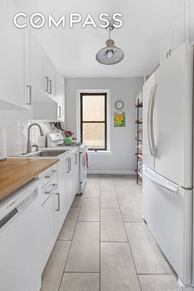 kitchen featuring white cabinetry, light tile patterned floors, white appliances, and tasteful backsplash