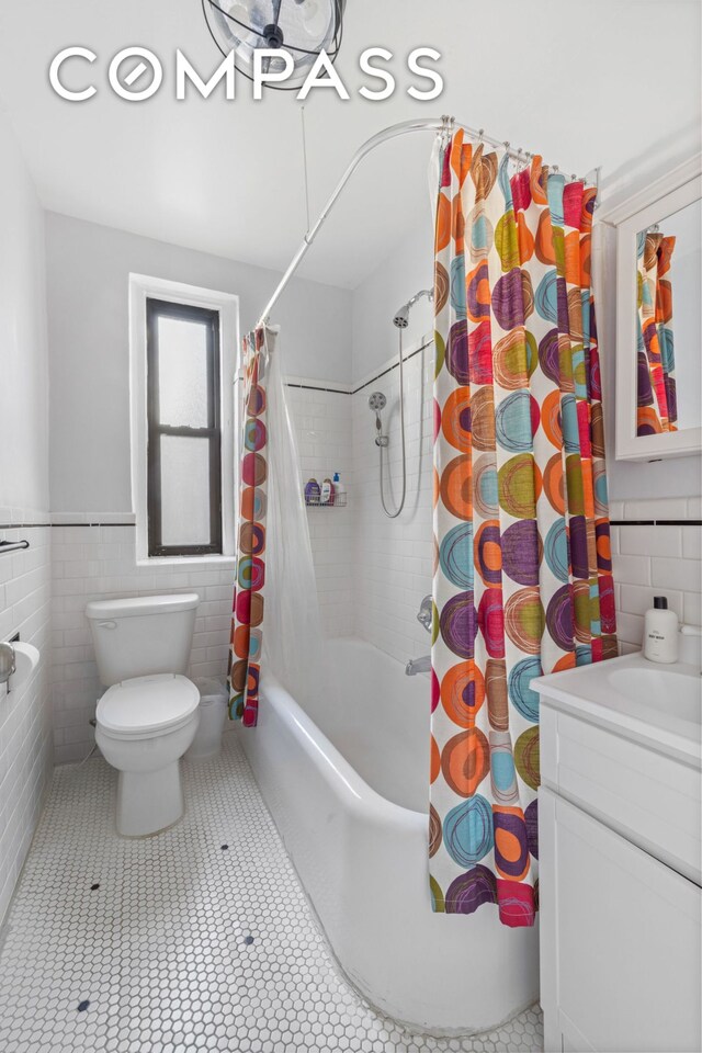 full bathroom featuring toilet, tile walls, vanity, shower / bathtub combination with curtain, and tile patterned flooring