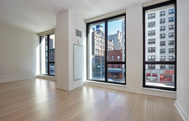 spare room with a wall of windows and light wood-type flooring