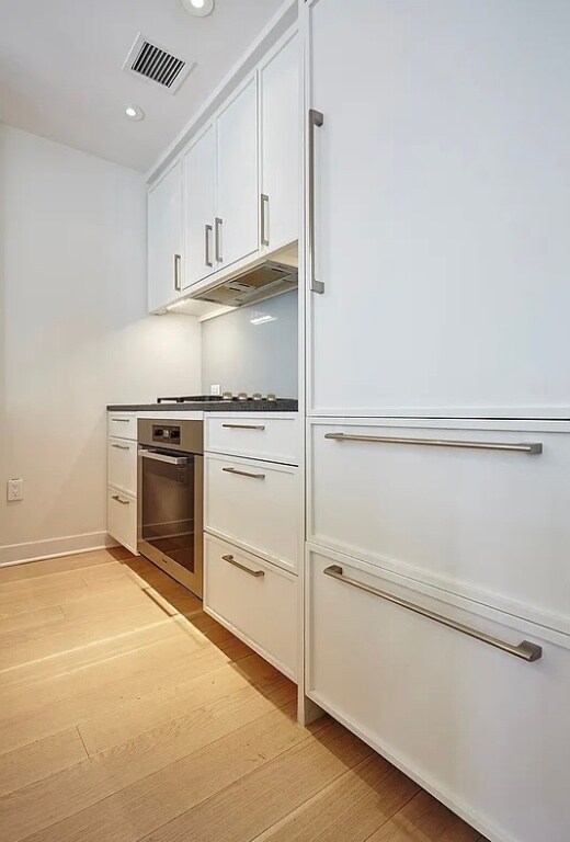 kitchen featuring white cabinetry, oven, and light hardwood / wood-style floors