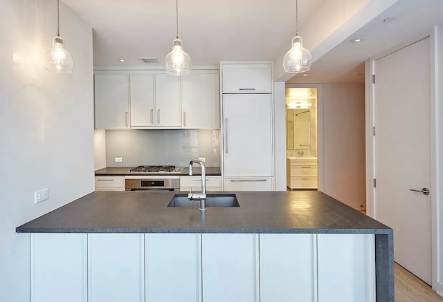 kitchen with pendant lighting, sink, white cabinets, and appliances with stainless steel finishes