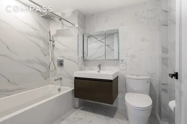 full bathroom featuring washtub / shower combination, toilet, marble finish floor, and vanity