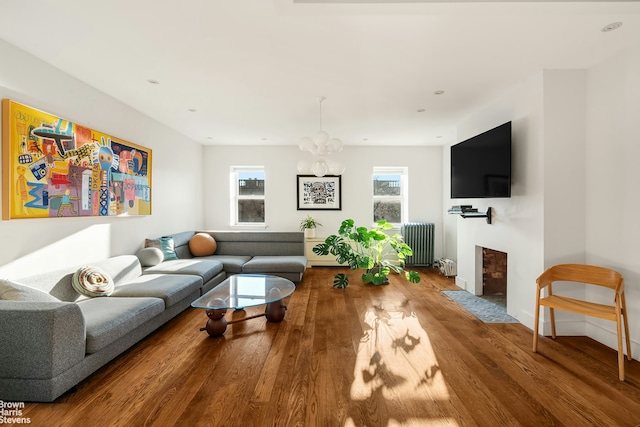 living room featuring plenty of natural light, radiator, a fireplace with flush hearth, and wood finished floors