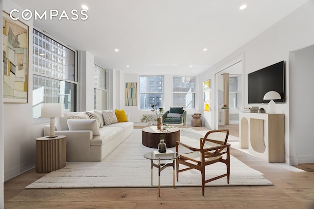 living area featuring light wood-type flooring, baseboards, and recessed lighting