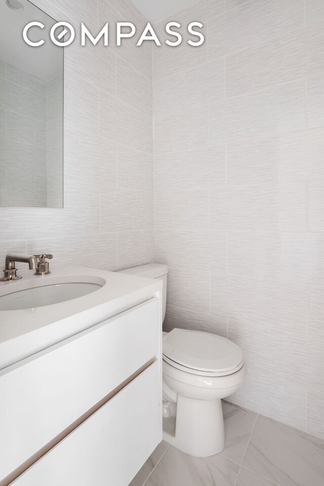 bathroom with tile walls, vanity, and toilet