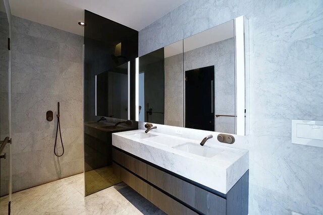 bathroom with vanity, a tile shower, and tile walls