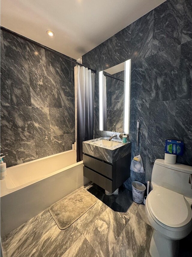 full bathroom with tile walls, vanity, toilet, and shower / bath combo with shower curtain