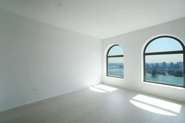 empty room featuring a water view and hardwood / wood-style floors