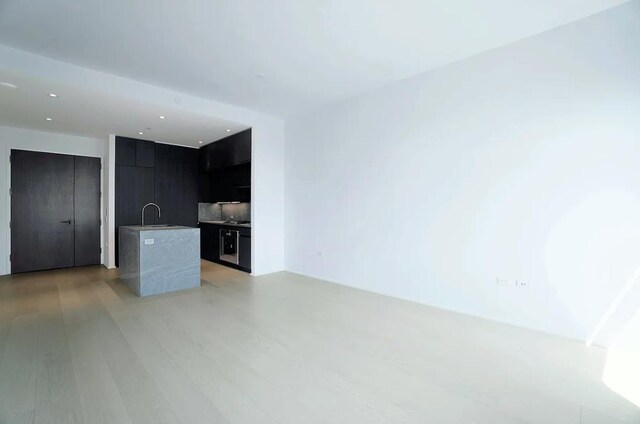 unfurnished living room featuring sink and light hardwood / wood-style floors