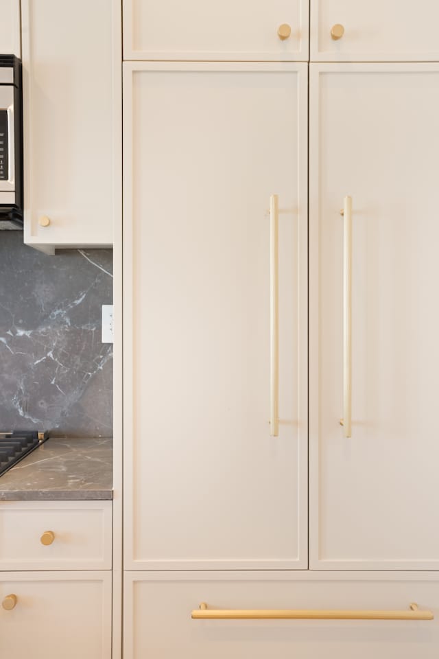 room details featuring tasteful backsplash and white cabinets