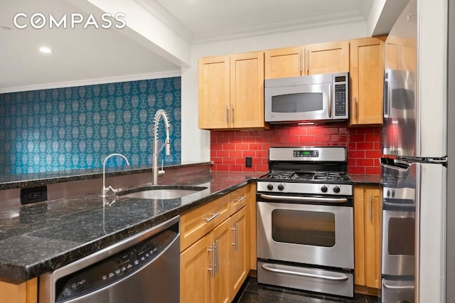 kitchen featuring crown molding, decorative backsplash, a sink, dark stone countertops, and stainless steel appliances