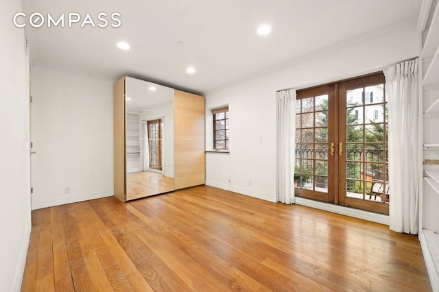 unfurnished room featuring light wood finished floors, crown molding, baseboards, recessed lighting, and french doors