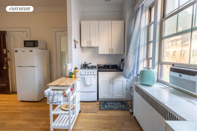 kitchen with white cabinetry, white appliances, sink, and light wood-type flooring