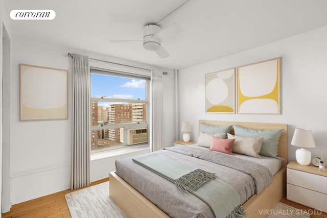 bedroom with cooling unit, light hardwood / wood-style flooring, and ceiling fan