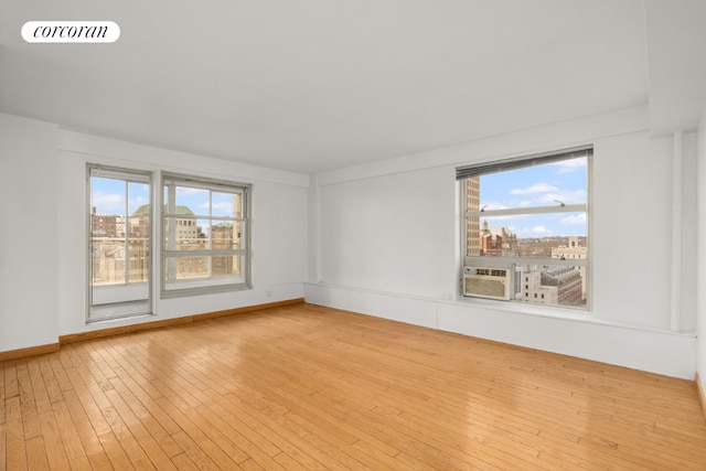 empty room featuring cooling unit, light wood-type flooring, and a wealth of natural light