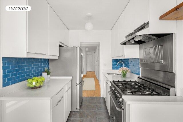 kitchen with high end stainless steel range oven, white cabinetry, tasteful backsplash, and light hardwood / wood-style flooring