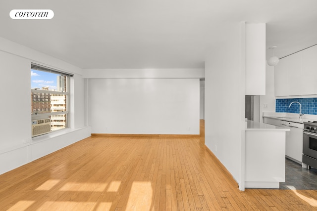 unfurnished living room featuring sink and light hardwood / wood-style floors