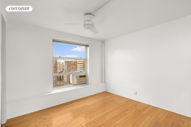 empty room featuring hardwood / wood-style floors, ceiling fan, and cooling unit