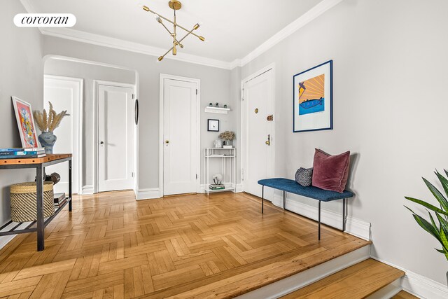 foyer with crown molding, parquet floors, and an inviting chandelier