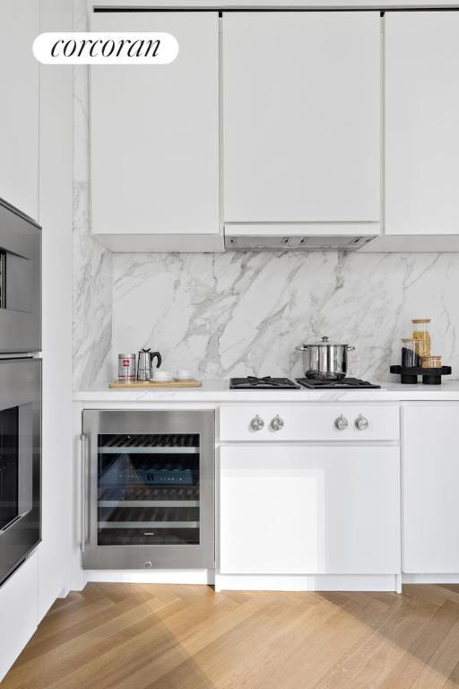 bar with gas stovetop, white cabinetry, stainless steel oven, and wine cooler