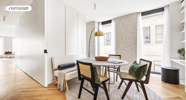 dining area with light parquet floors, floor to ceiling windows, and a healthy amount of sunlight