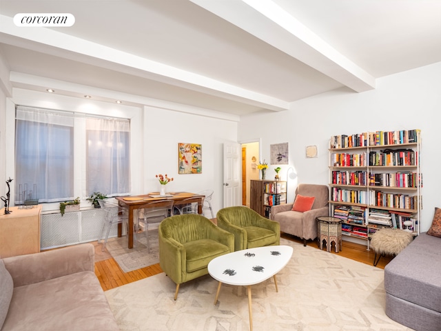 living area with visible vents, beam ceiling, and wood finished floors