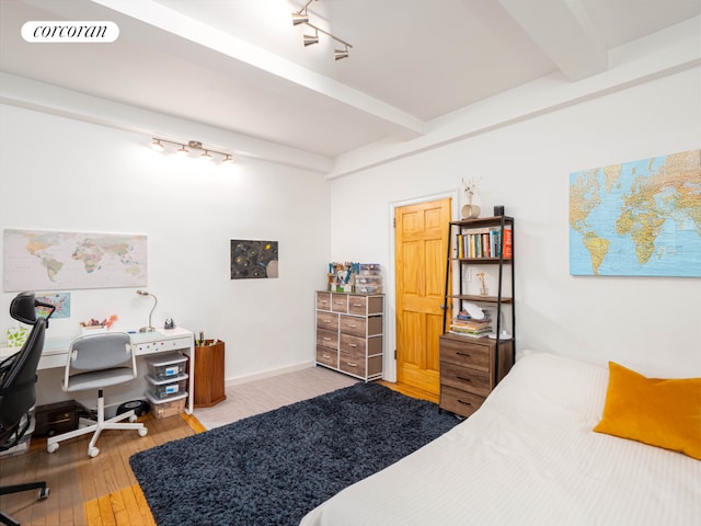 bedroom with visible vents, track lighting, beam ceiling, and wood finished floors