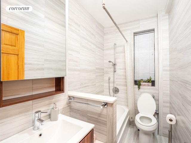 full bathroom featuring vanity, washtub / shower combination, toilet, and tile walls