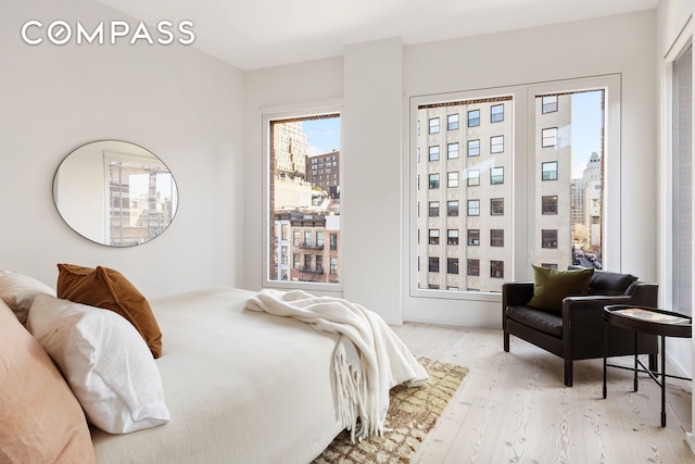 bedroom featuring light wood-style flooring and a city view