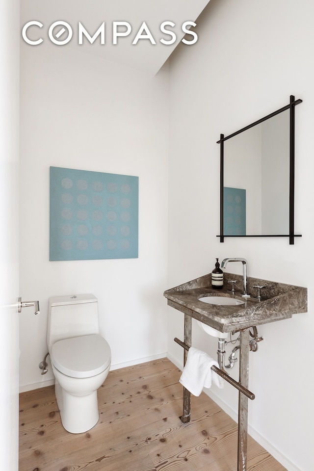 bathroom featuring baseboards, a sink, toilet, and wood finished floors