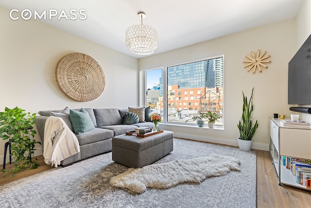 living room featuring a notable chandelier, baseboards, and wood finished floors