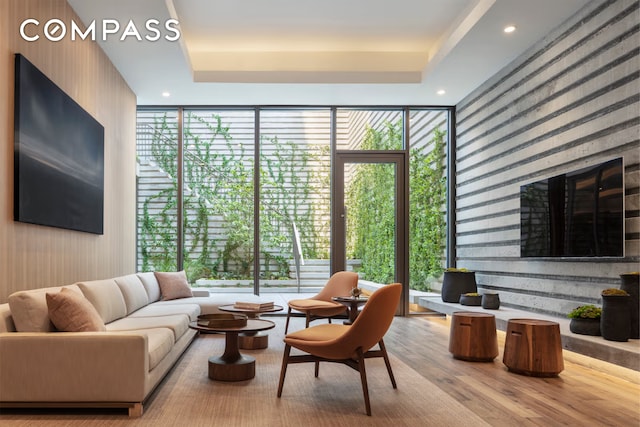 living room featuring expansive windows, a raised ceiling, and wood finished floors