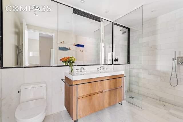 bathroom featuring a sink, tiled shower, toilet, and double vanity