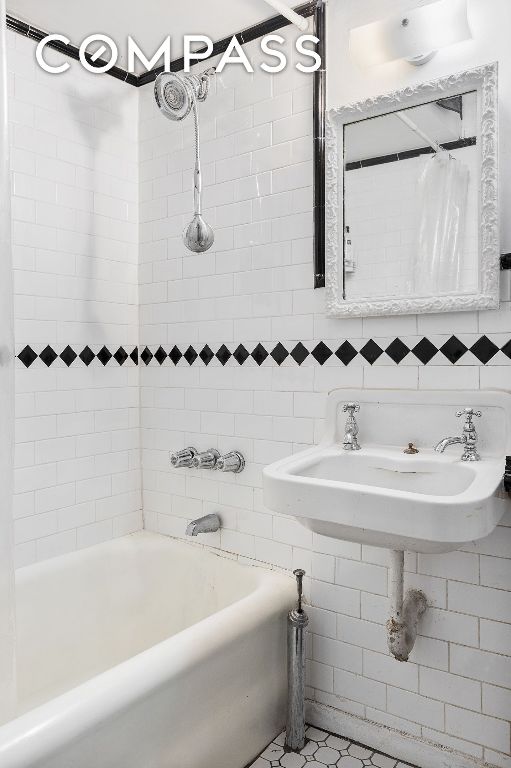 bathroom featuring shower / tub combo with curtain, sink, tile walls, and backsplash