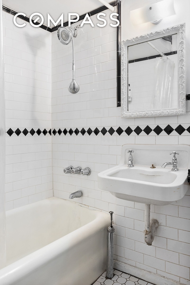 full bathroom with tasteful backsplash, tile walls, shower / tub combo with curtain, and a sink