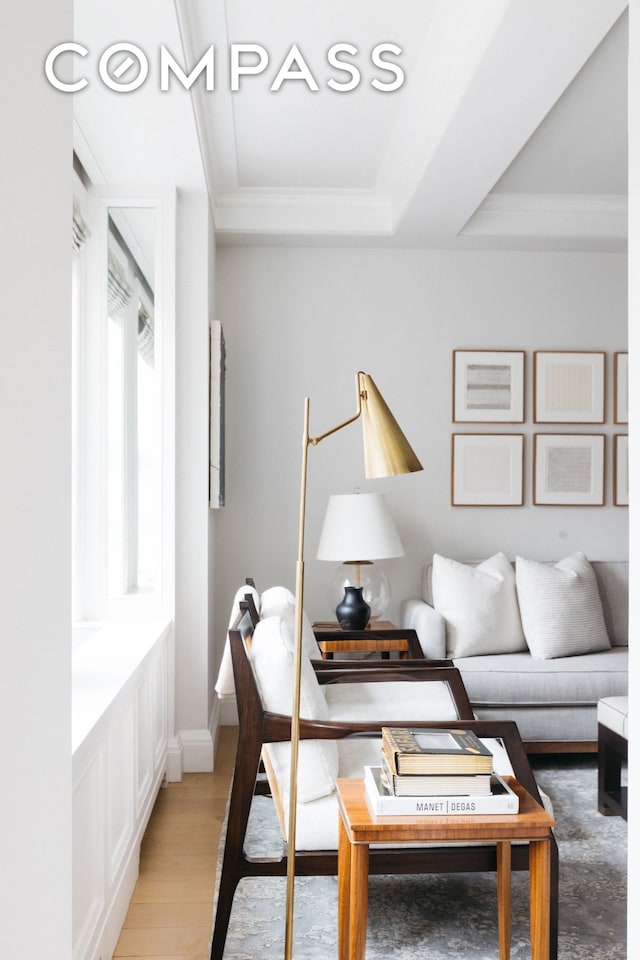 living room featuring light wood-style flooring, crown molding, baseboards, and a raised ceiling