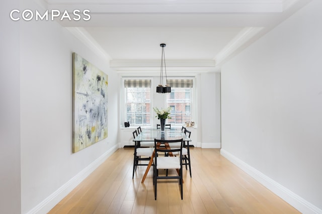 dining area featuring light wood-style flooring, crown molding, and baseboards