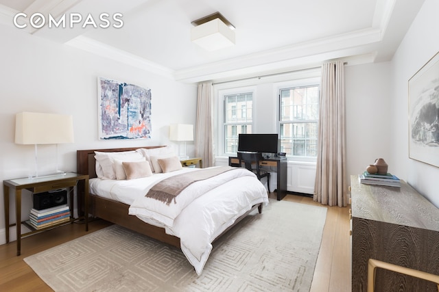 bedroom with a tray ceiling and light wood-style flooring